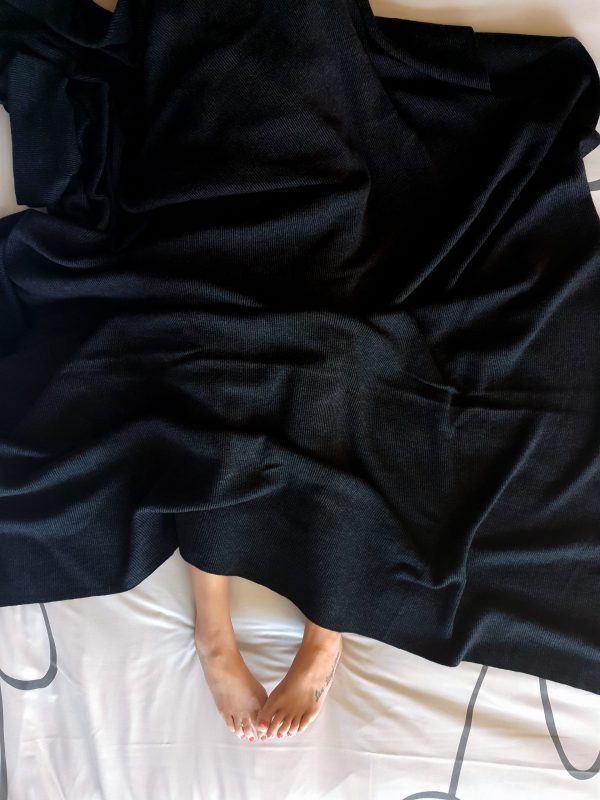 Charcoal Merino Wool Blanket draped over someone, revealing a cosy moment with contrasting colours and a mini stripe design.