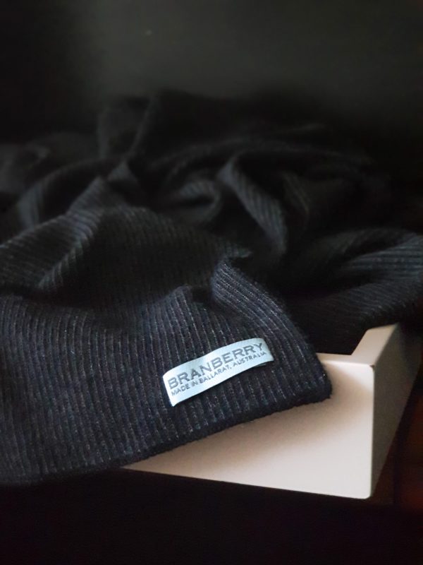 Close-up view of Charcoal Merino Wool Blanket corner, showcasing its mini stripe feature and Branberry brand label.