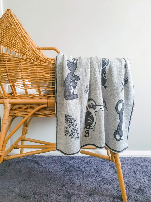 Australian Animals Blanket in Quartz draped over a rattan bassinet