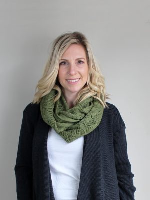 A lady standing indoors wearing a Olive Green Branberry Wool Infinity Scarf