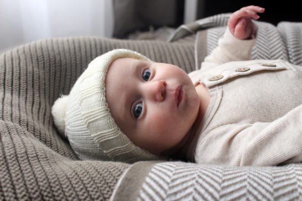 A baby wearing a neutral white Frankie Beanie, showing the rib folded up for a classic look.