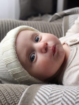 A baby wearing a neutral white Frankie Beanie, showing the rib folded up for a classic look.