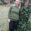 A lady leaning against a tree outside in the bush wearing a Ballarat Gold branded Australian made pure merino wool Sophie 1010 jumper in Olive green