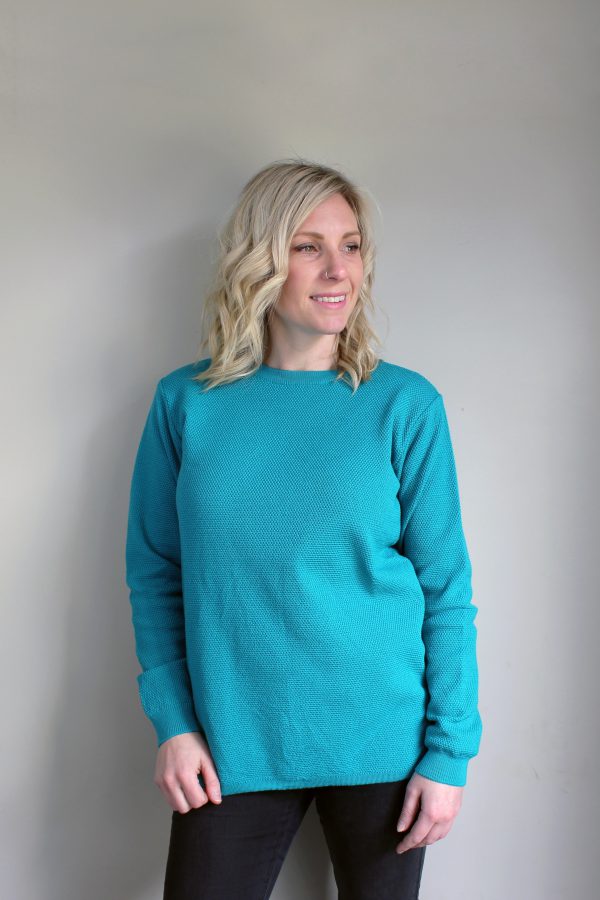 A lady wearing an Australian Made, Ballarat Gold merino wool moss crew jumper in Aqua