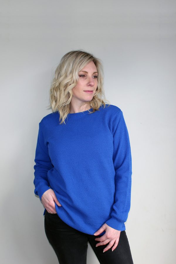 A lady wearing an Australian Made, Ballarat Gold merino wool moss crew jumper in Tahiti Blue