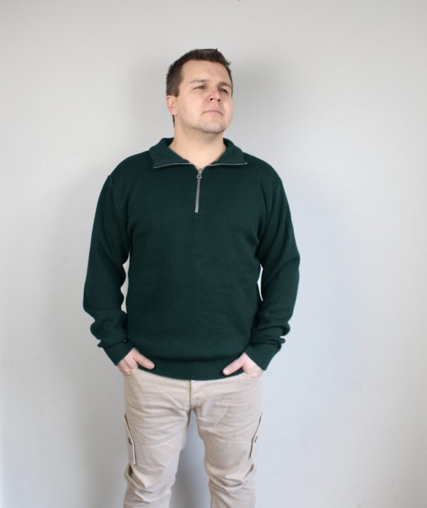 A man standing indoors wearing an Australian Made, pure merino woollen Branberry knitted jumper with zip neck in Forest Green.