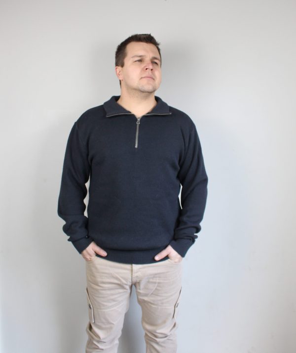 A man standing indoors wearing an Australian Made, pure merino woollen Branberry knitted jumper with zip neck in Bond Grey.