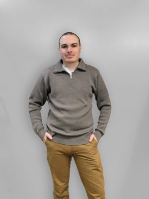 A man standing indoors wearing an Australian Made, pure merino woollen Branberry knitted jumper with zip neck in Mocha Brown.