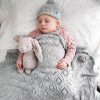 Branberry Heirloom Blanket in Smoke, a baby laying on their back, sleeping under the blanket with a matching Pure Wool Frankie Beanie and a snuggle bunny teddy