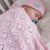Branberry Heirloom Blanket in Pink Silk, a close-up view of a baby sleeping in a cot with the blanket, a blue dummy, and a matching Pure Wool Frankie Beanie