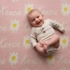 A laughing baby laying on a Personalised Name Blanket with Daisy flowers in a Pastel Pink colour. Made from Pure Australian Merino Wool and Made in Australia.
