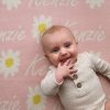 A baby laying on a Personalised Name Blanket with Daisy flowers in a Pastel Pink colour. Made from Pure Australian Merino Wool and Made in Australia.