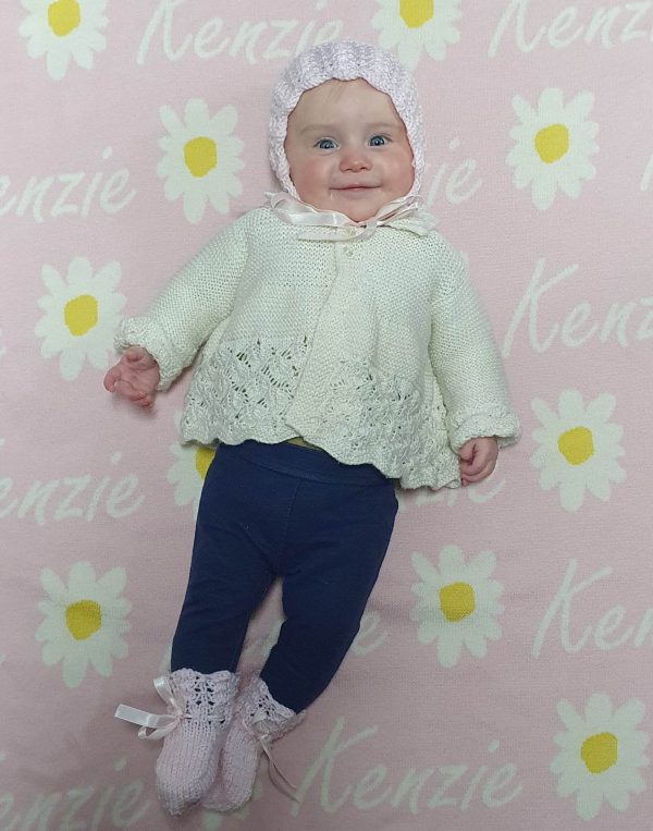 A baby laying on a Personalised Name Blanket with Daisy flowers in a Pastel Pink colour. Made from Pure Australian Merino Wool and Made in Australia.
