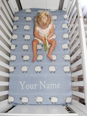 A toddler sitting on top of a Personalised Pure Australian Merino wool Sheep blanket in light blue, reading a book.