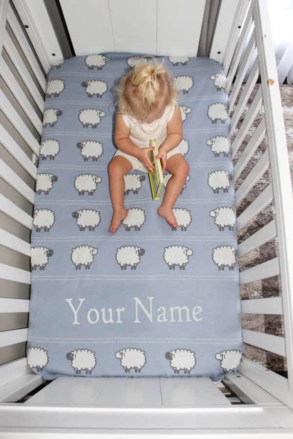 A toddler sitting on top of a Personalised Pure Australian Merino wool Sheep blanket in light blue, reading a book.