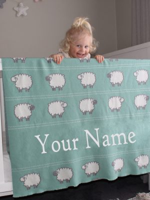 A toddler leaning on her Personalised Pure Australian Merino wool Sheep blanket in Seafoam Green, that's placed over a cot