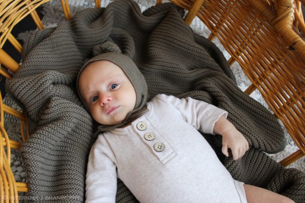 A baby laying in a bassinet ontop of an Australian Made Branberry, Plain Garter Blanket in Pecan