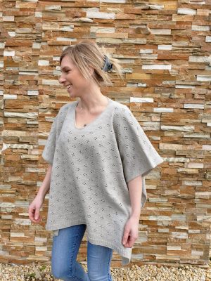 A woman walking in a smoke grey Harlow Merino Wool Poncho, showcasing the garment's elegant swing as she moves.