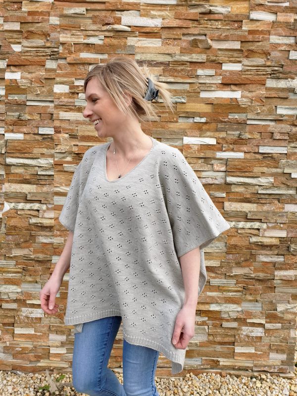 A woman walking in a smoke grey Harlow Merino Wool Poncho, showcasing the garment's elegant swing as she moves.